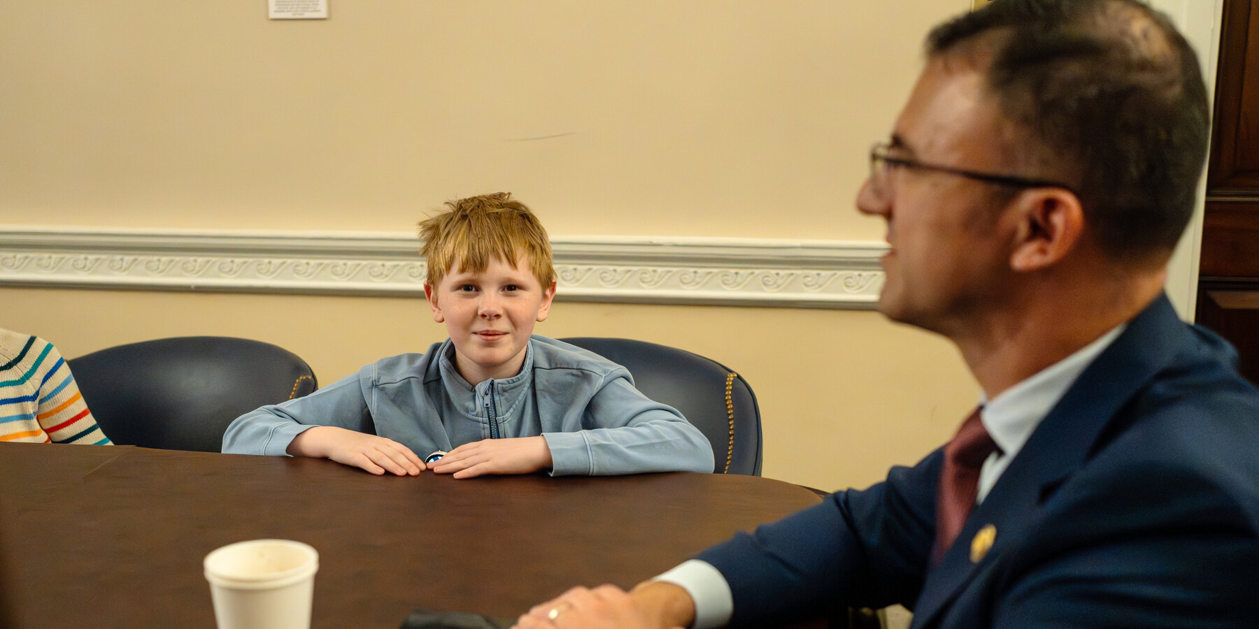 A young advocate with Angelman syndrome seated at a table with a member of Congress