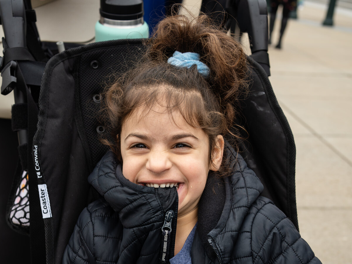 A young girl with Angelman syndrome laughing in her wheelchair outside the meeting hotel